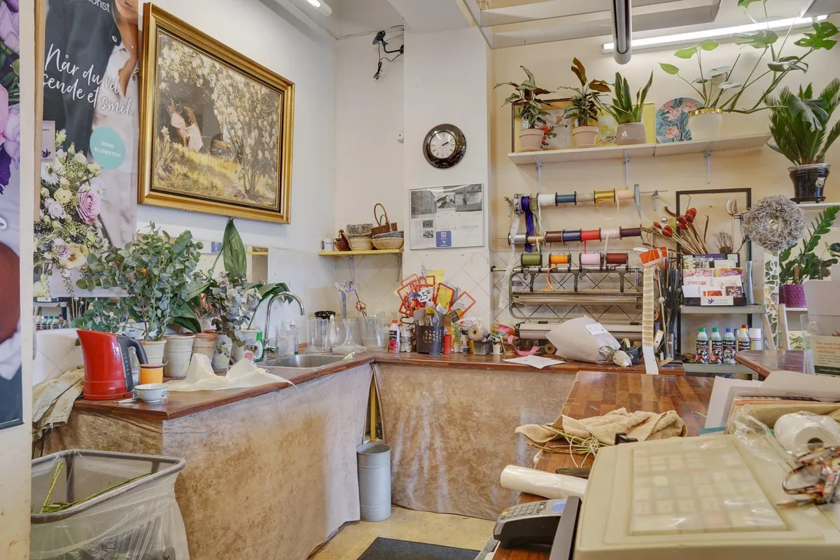 Flot butik med blomster og planter, gulvbelægning og udsmykning, og en indretning med hylder, plantekasser, og en