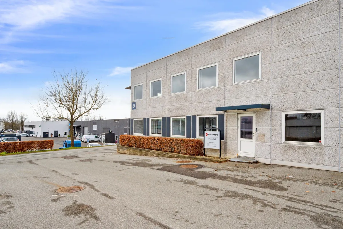 Kontorby i Skovlunde med buske foran døren og parkeringsplads med nummer 9, og et Signode-skilt på facaden