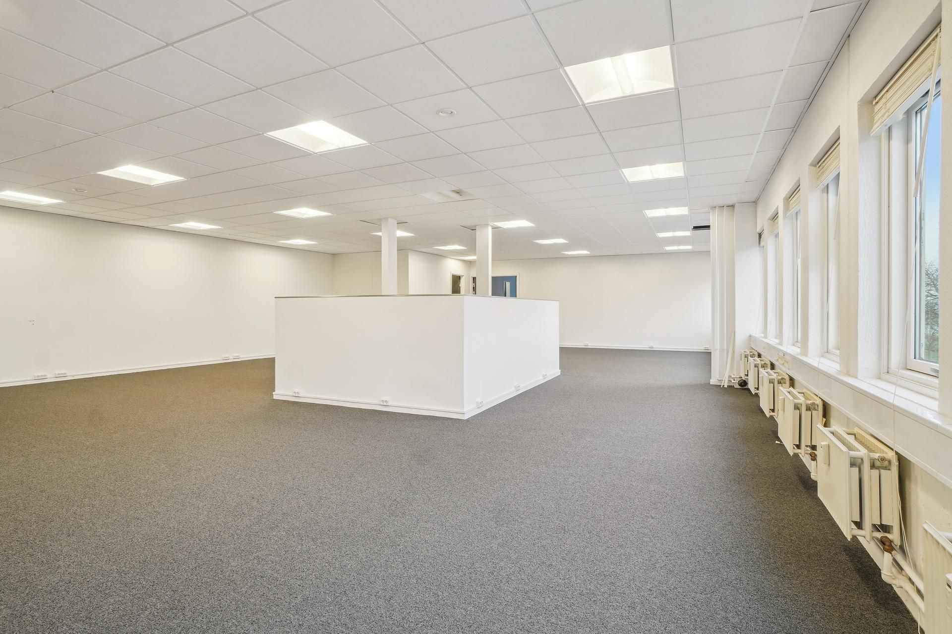 Et lyst og velholdt kontorlokal på 327 m² med hvidt loft, lysegule vægge og lysegrå gulvbelægning. Store vinduer med