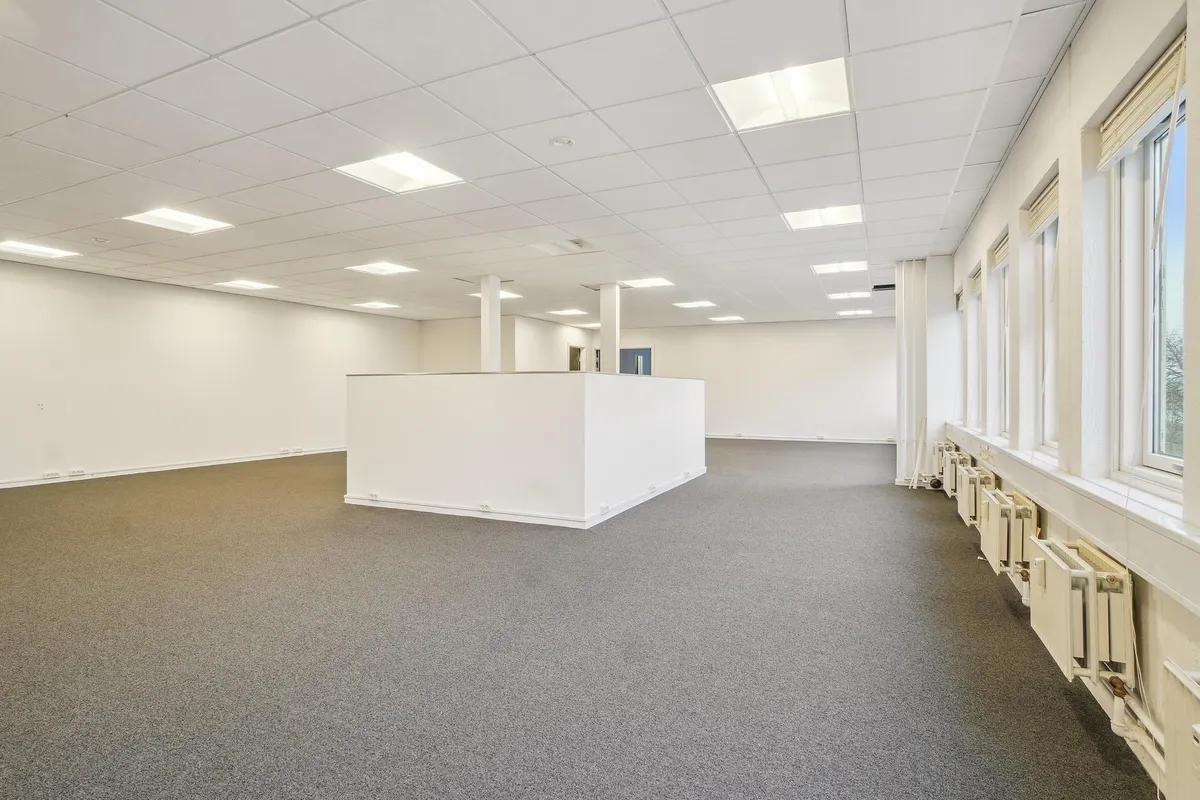 Et lyst og velholdt kontorlokal på 327 m² med hvidt loft, lysegule vægge og lysegrå gulvbelægning. Store vinduer med