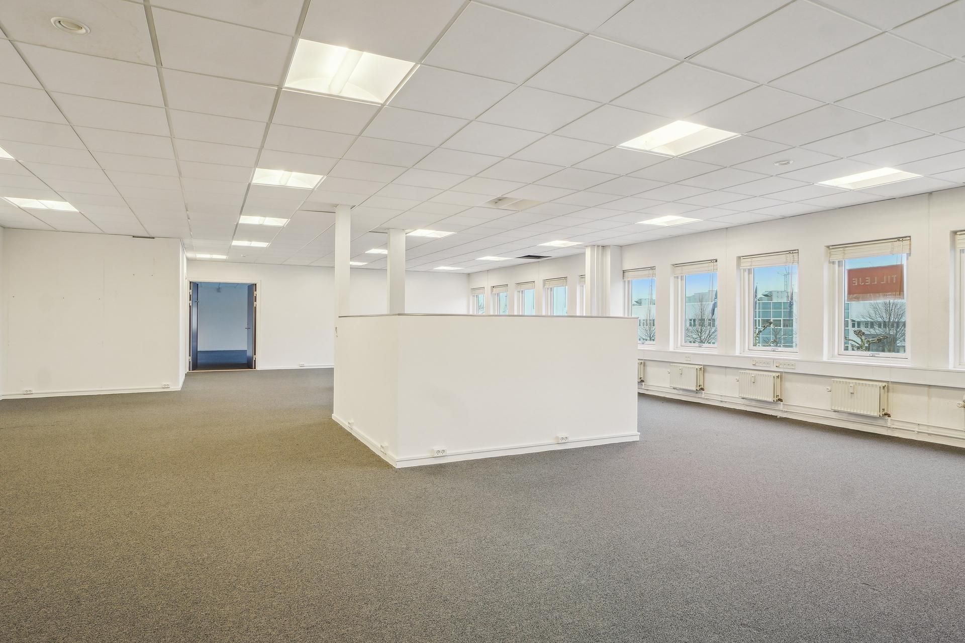 Lyst og velholdt kontorlokal på 327 m² med store vinduer og moderne gulvbelægning. Alle vægge er hvide og der er hvide