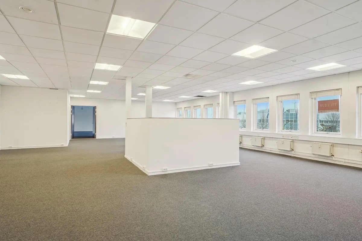 Lyst og velholdt kontorlokal på 327 m² med store vinduer og moderne gulvbelægning. Alle vægge er hvide og der er hvide