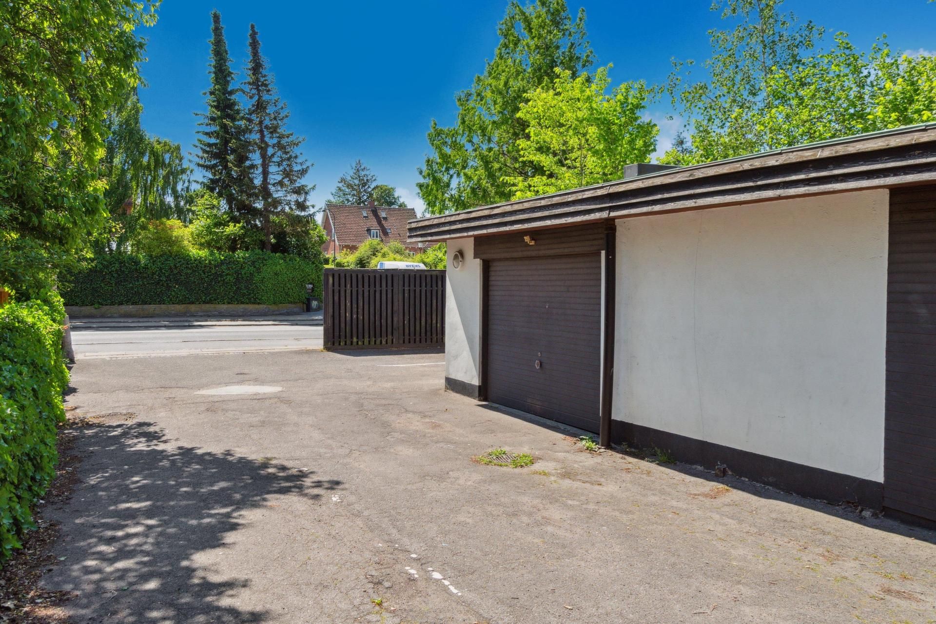 Garage med to parkeringspladser og indkørselsmulighed. Væggene er malet i hvidt og brunt. Der er et enkelt garagedør og en