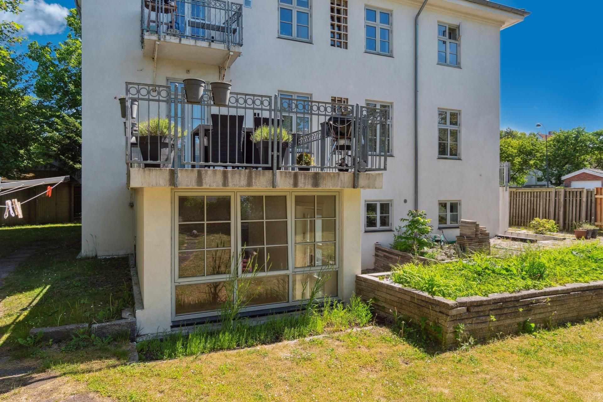 Kontorbyggeri i Hellerup med balkon og terrasse med plantepoteter og have. Glasdøre og vinduer samt grønne græsplæner og