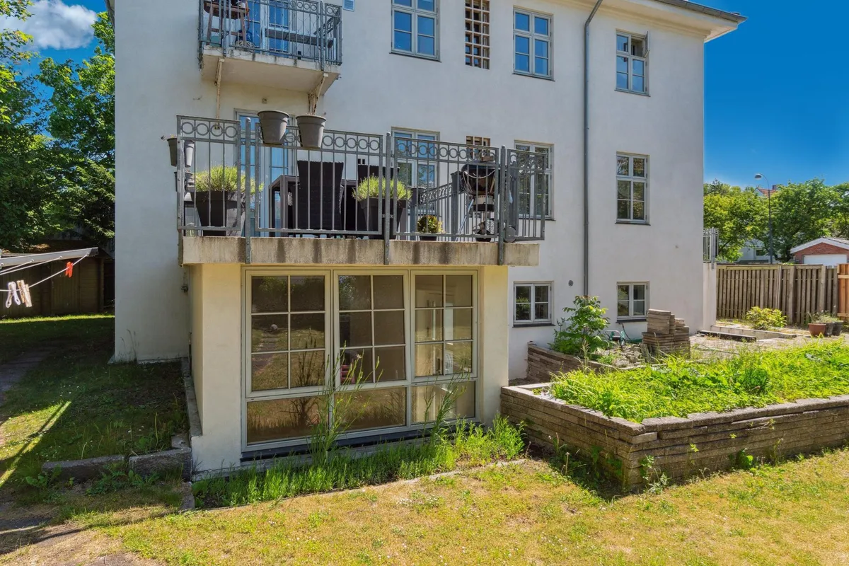 Kontorbyggeri i Hellerup med balkon og terrasse med plantepoteter og have. Glasdøre og vinduer samt grønne græsplæner og