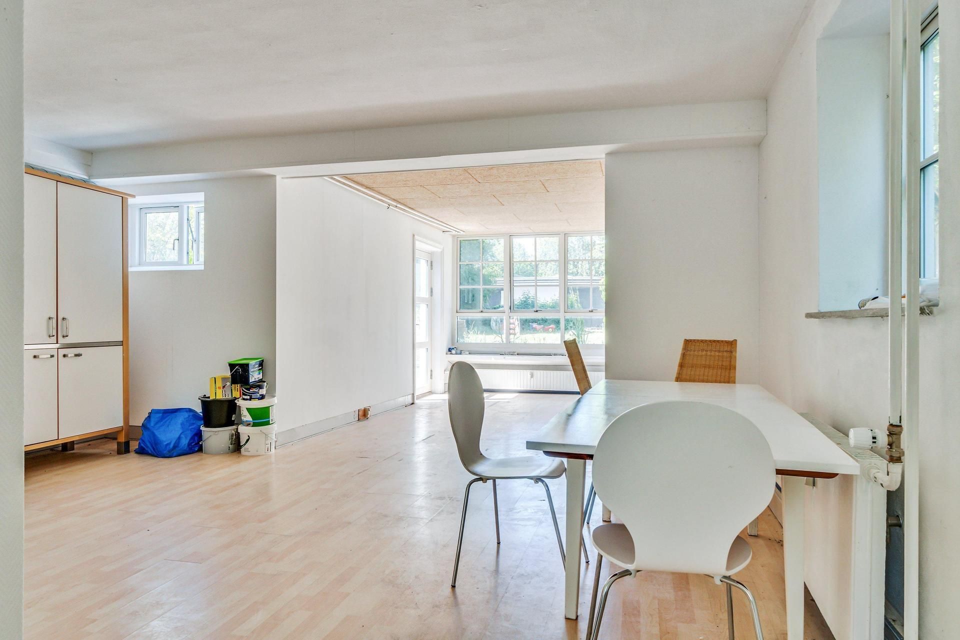 Lyst og luftigt kontor med højt til loftet og masser af vinduer, møbler og ting i et rum, et bord og stole