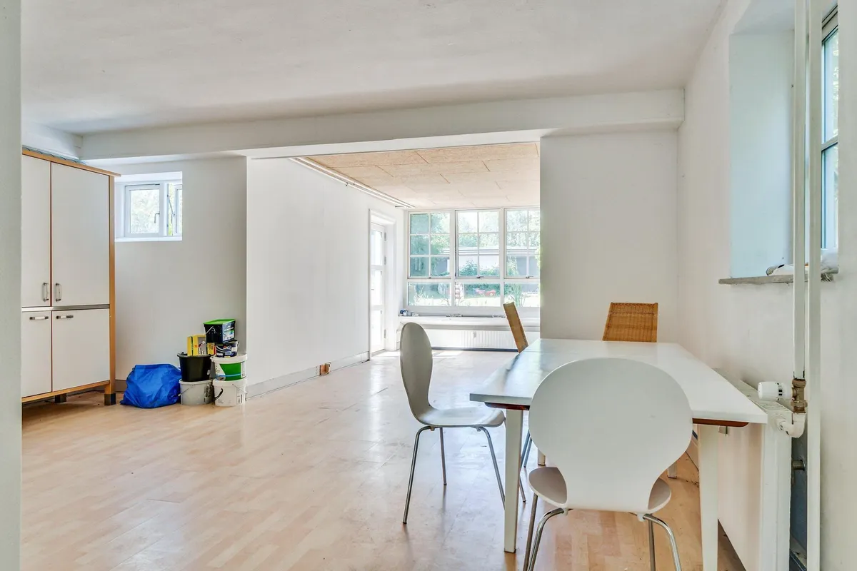 Lyst og luftigt kontor med højt til loftet og masser af vinduer, møbler og ting i et rum, et bord og stole