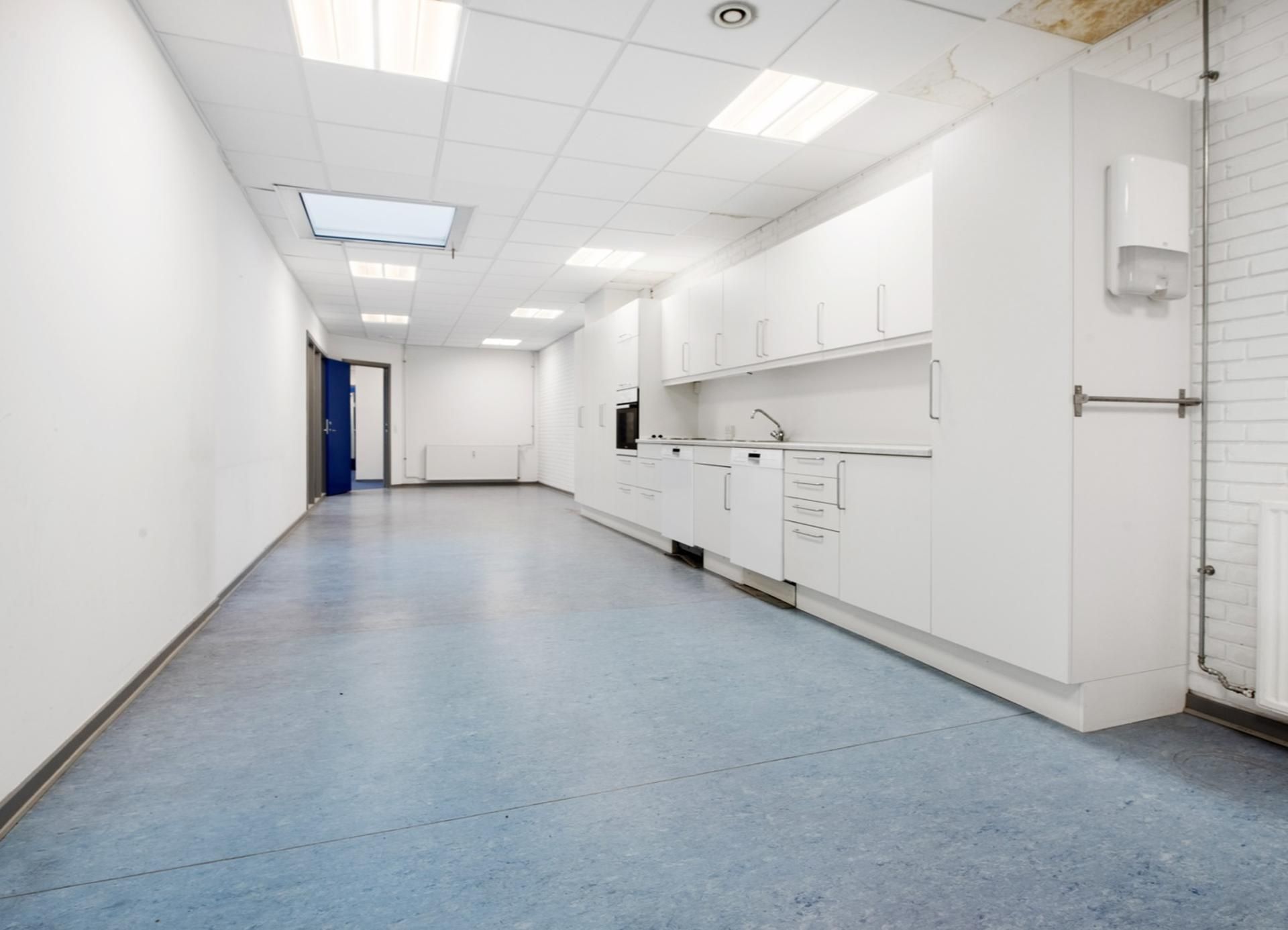 Indflytningsklare kontorlokaler med hvide vægge og lofter samt lysegule gulve. Der er flere hvide skabe og en stående
