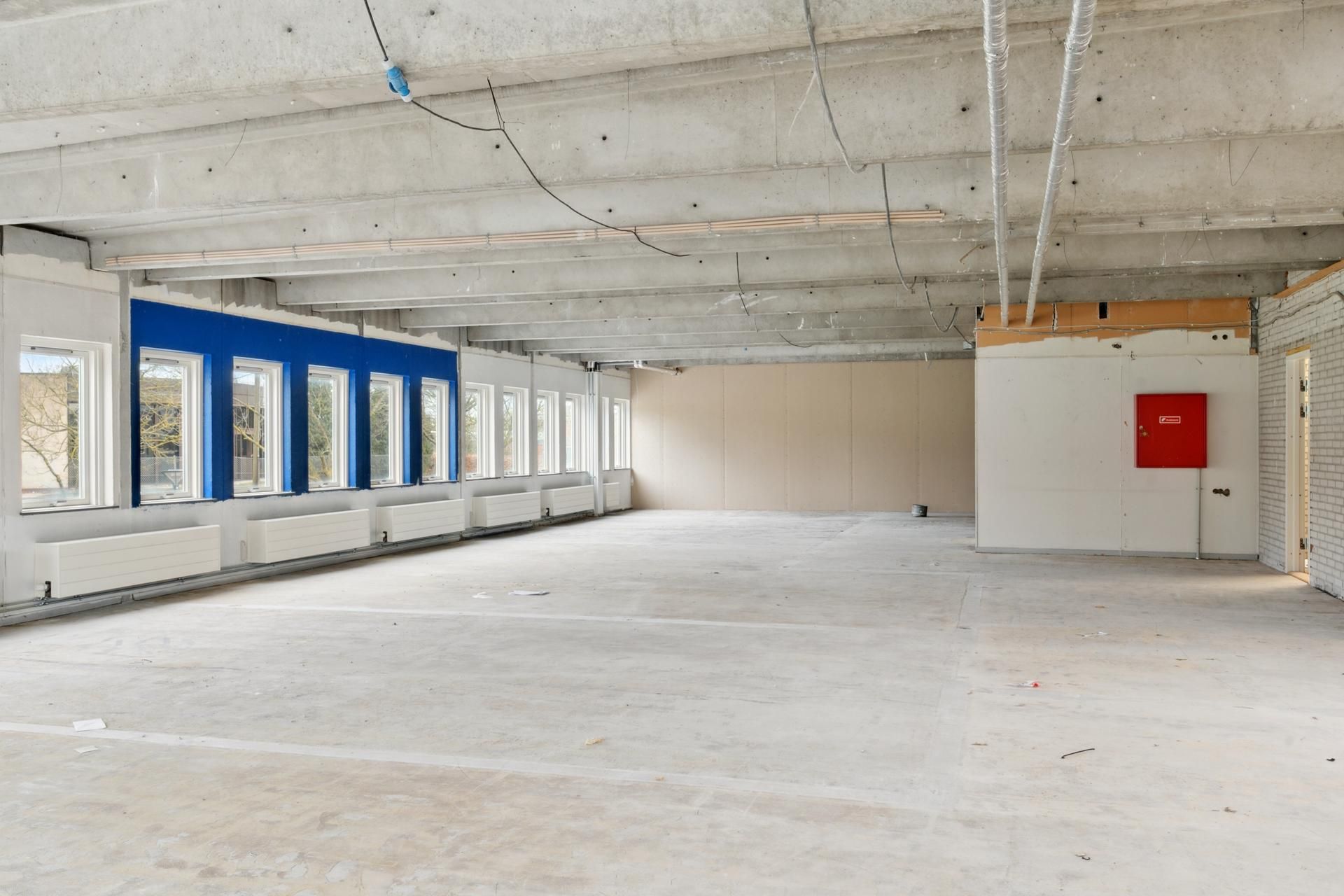 Kontorområde med hvide vægge, gulv og loft samt blå døre og vinduer, samt rød brandslukker