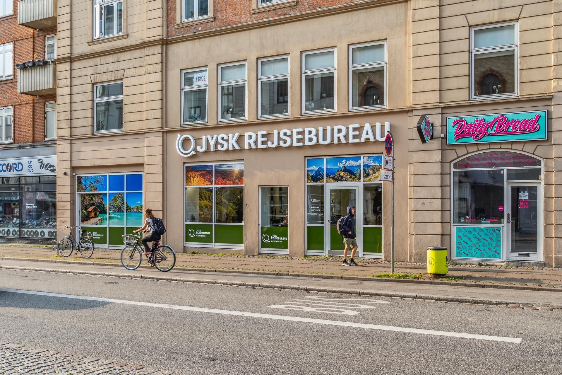 Cykelturister passerer forbi QJysk Rejsebureau og Daily Bread på Vesterbrogade, hvor der er udsigt til naturskønne