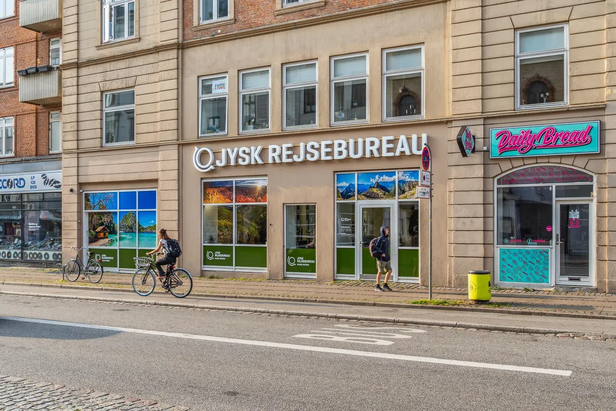 Cykelturister passerer forbi QJysk Rejsebureau og Daily Bread på Vesterbrogade, hvor der er udsigt til naturskønne