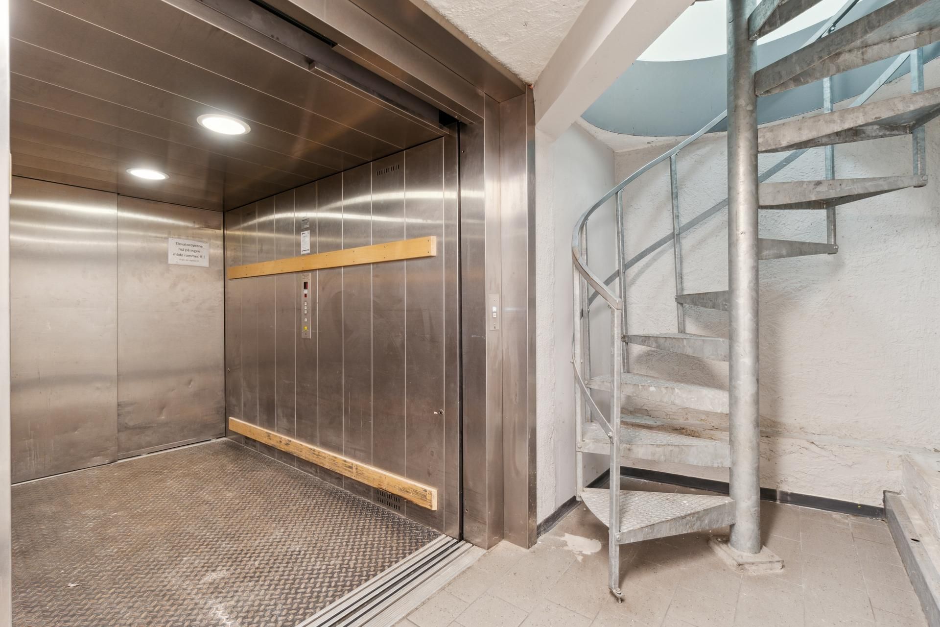 En højloftet lager med elevator og spiraltrappe til opgang til øverste etage.