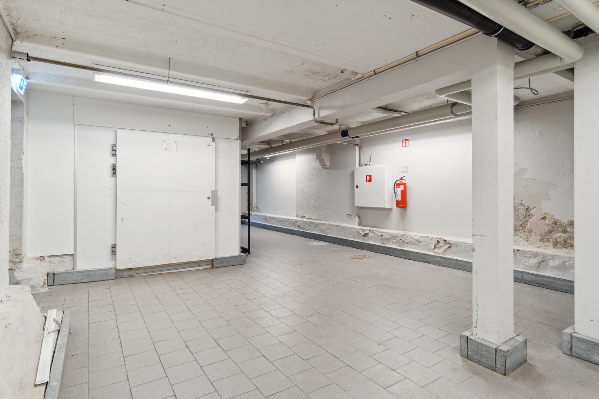 Lager med højloft og fire hvide søjler samt ildslukker og adgangsdør udenfor