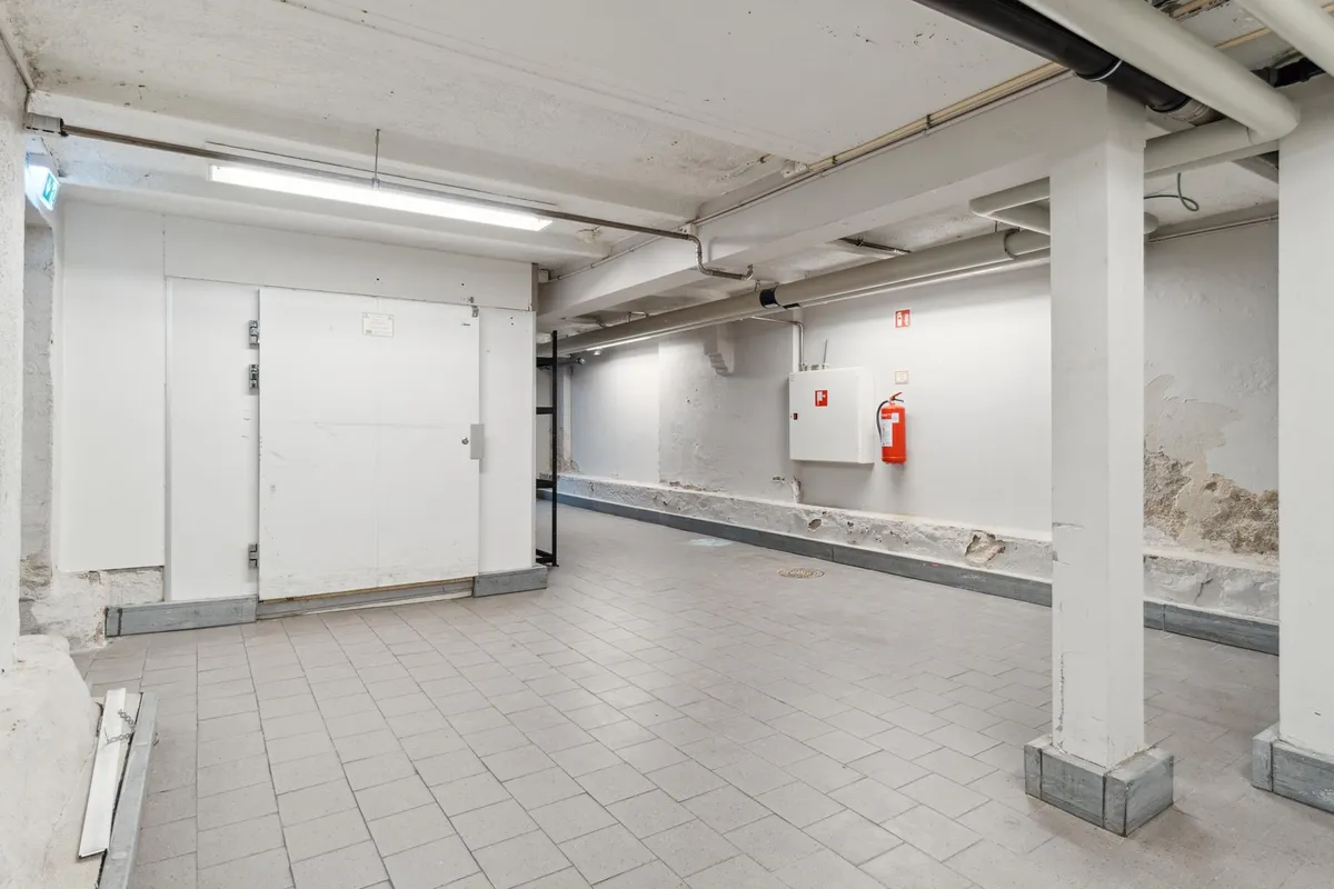 Lager med højloft og fire hvide søjler samt ildslukker og adgangsdør udenfor