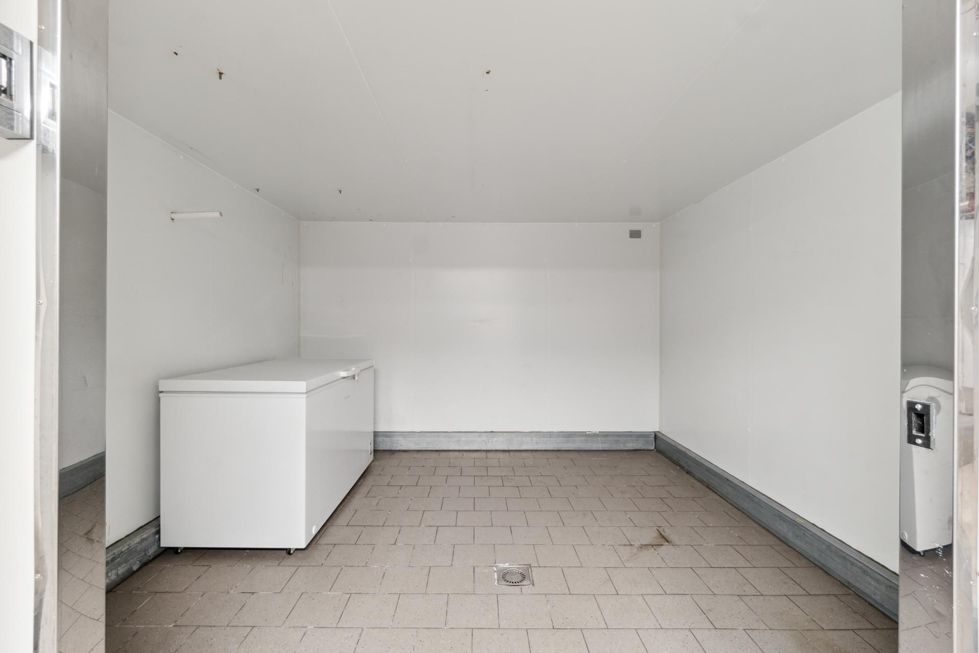 Lager med iskuffer og højloft, hvilket giver plads til lagervarer. Til venstre er der en høj køleskab, og i højre side er