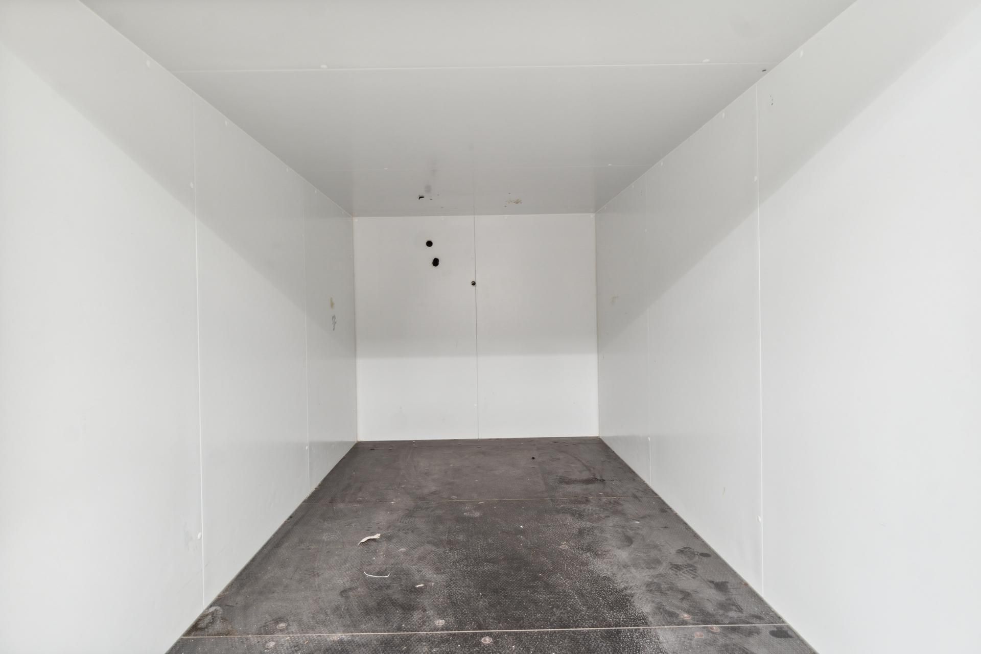 Lager med hvide vægge og cementgulv samt to døre i midten. Lageret ligger centralt på Vesterbrogade.