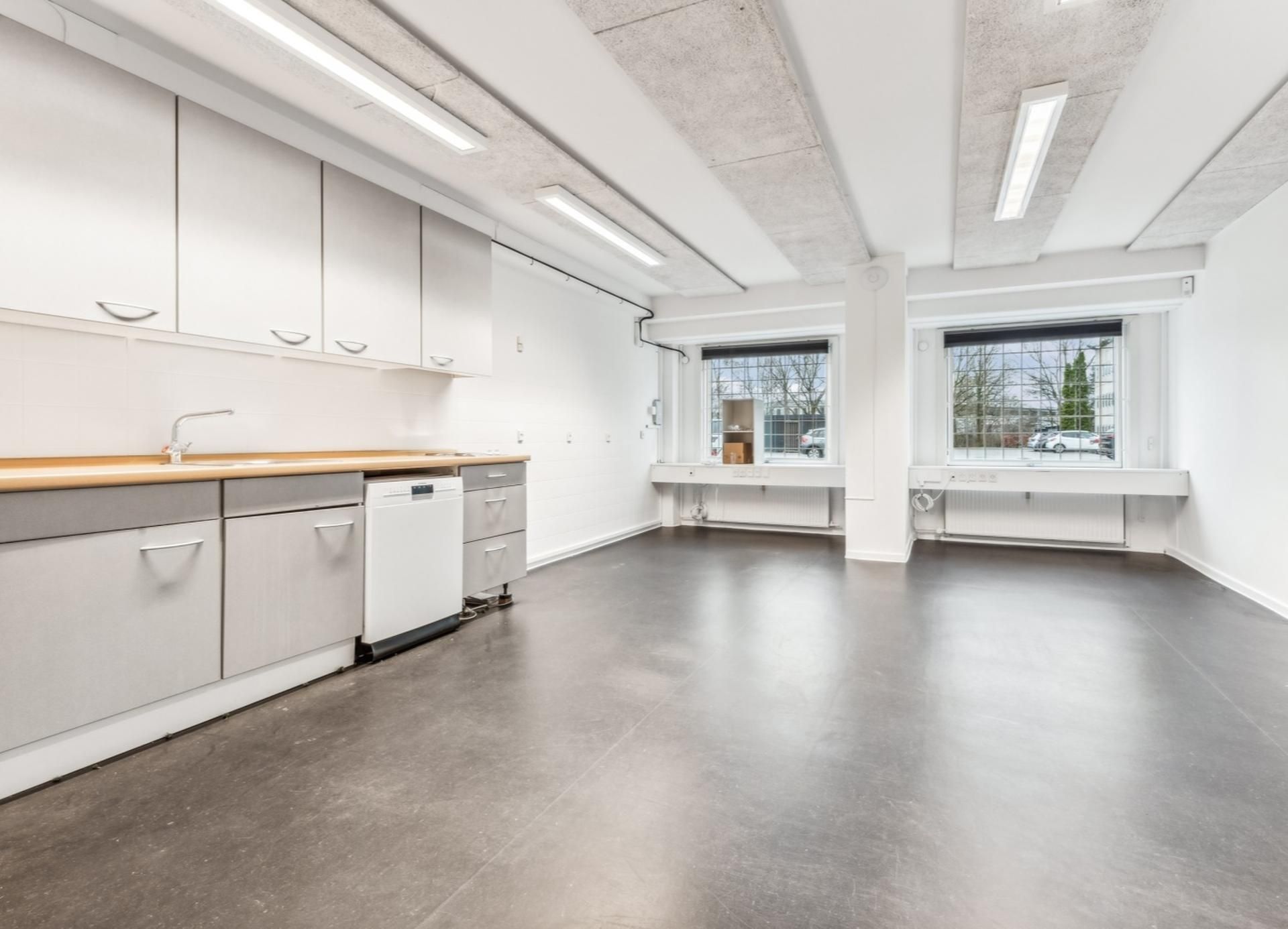 Et nyt renoveret køkken med moderne hvide lofter og gulv samt lyse vindue.