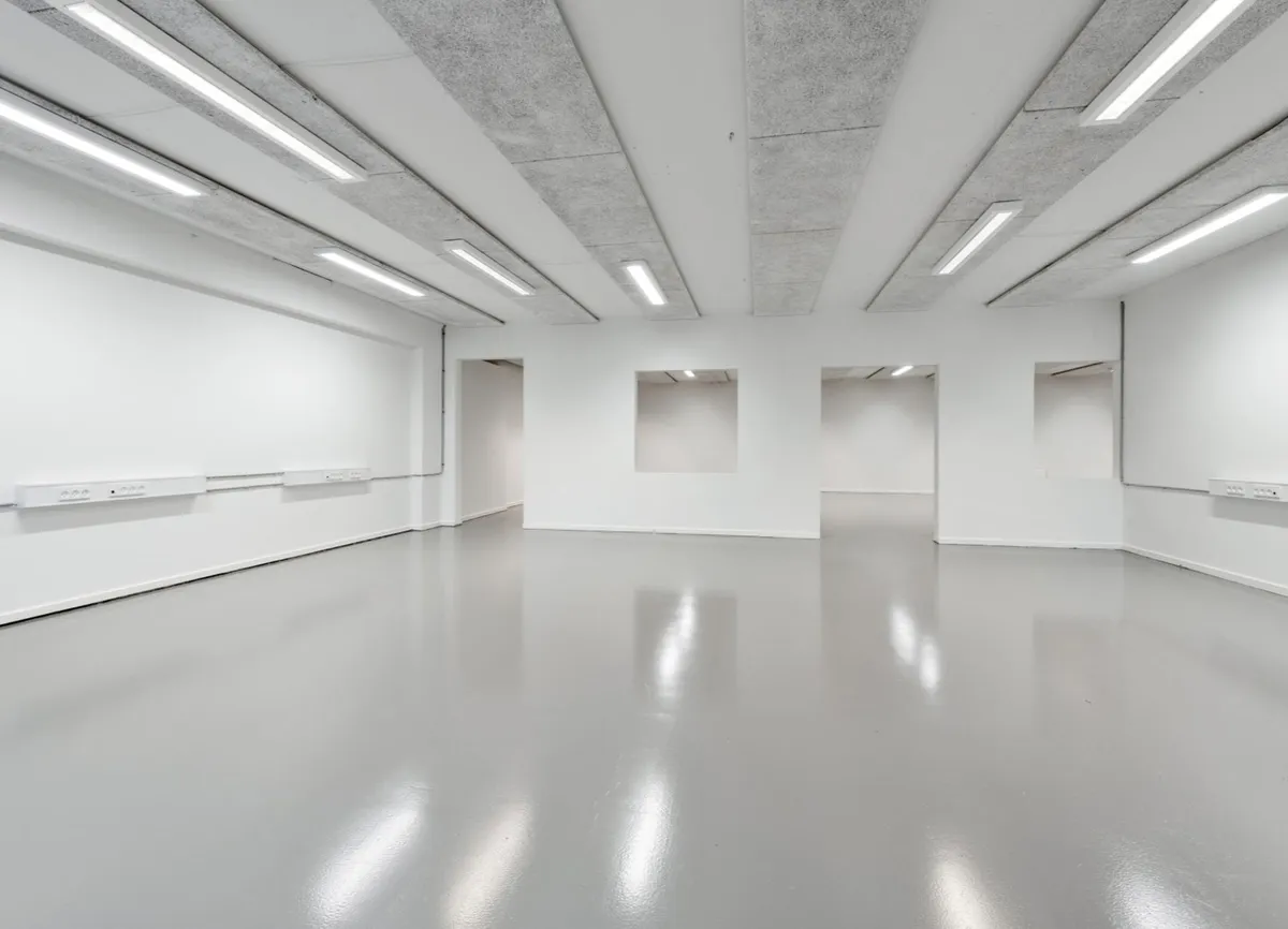 En stor, hvid stue med blanke gulve og vægge, hvor flere lysekroner er monteret på loftet