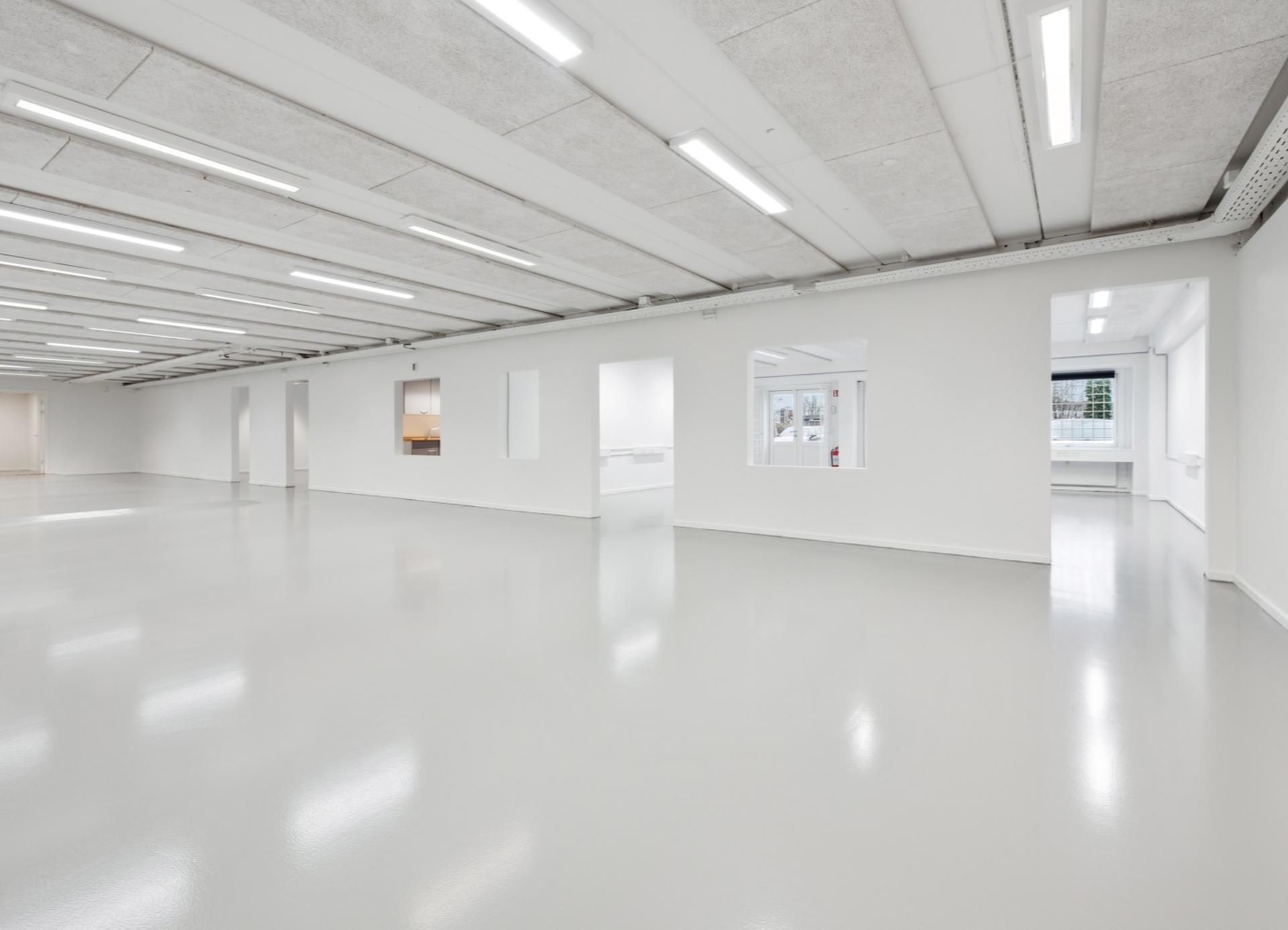 Ren, stor, hvid erhvervslejemål med højt til loftet og moderne belysning