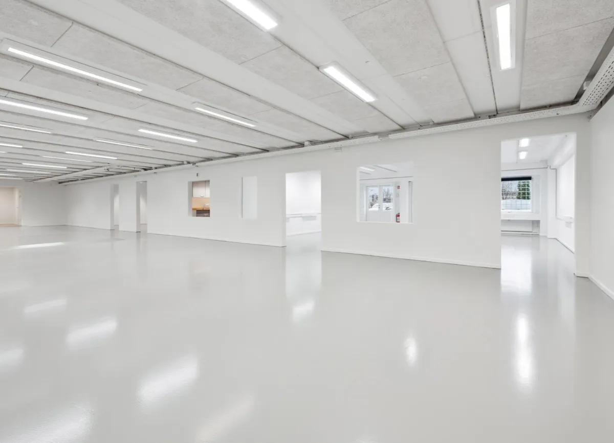 Ren, stor, hvid erhvervslejemål med højt til loftet og moderne belysning