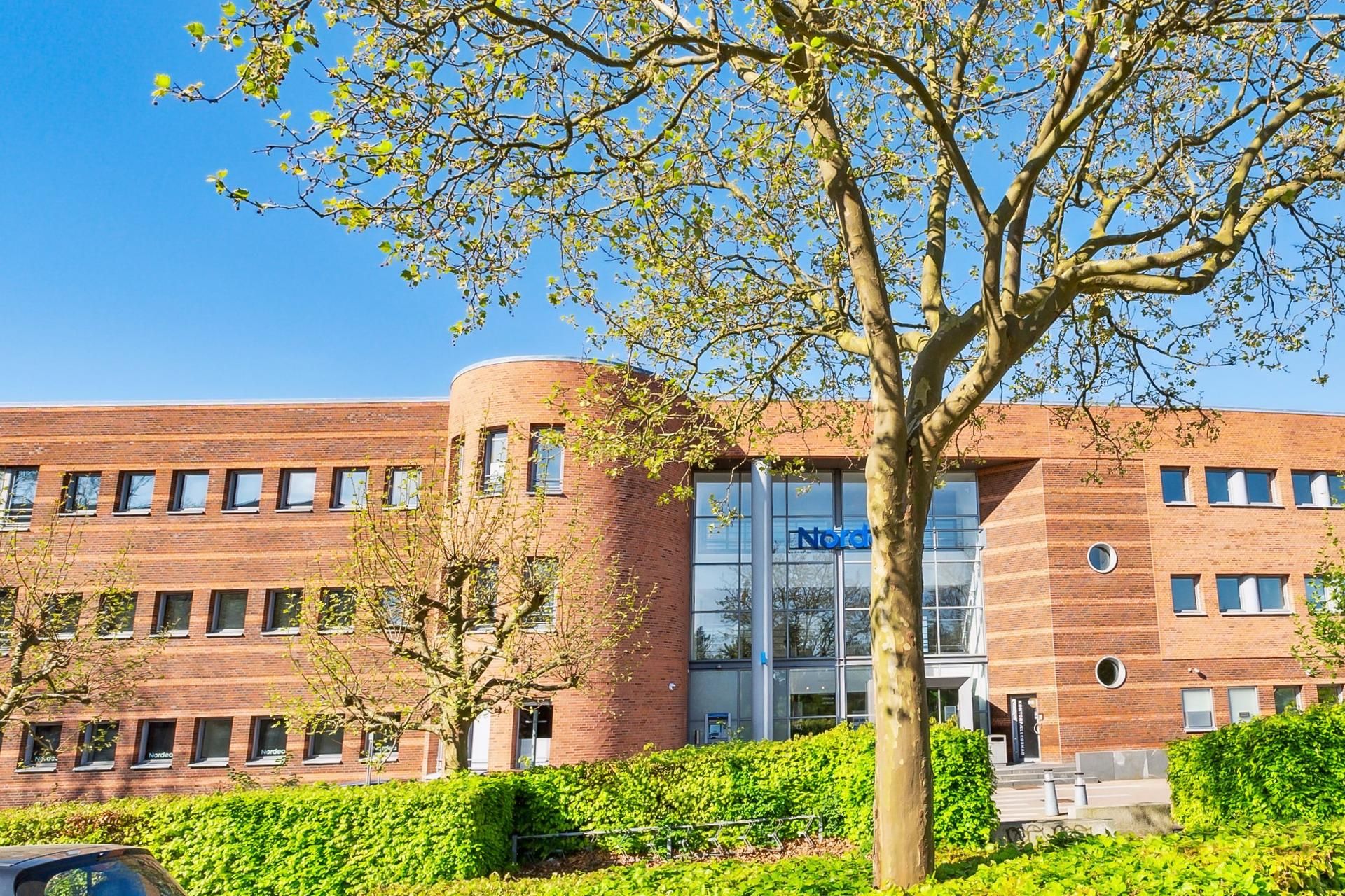Kontorbygning med røde mursten og glasvinduer med teksten Nordea og logoet på facaden