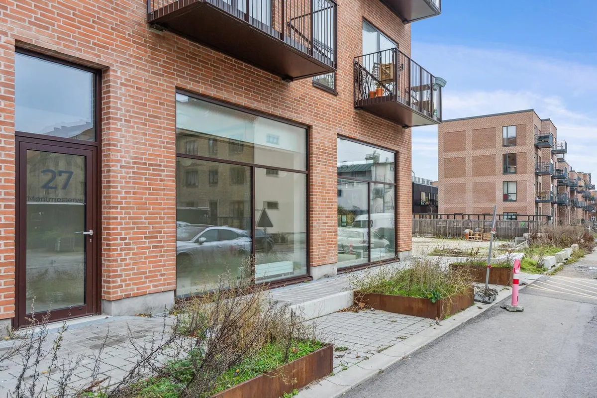 Moderne lokaler i kvarteret med nummer 27, glasruder og dør med nummer 27, plantekasser og søjler langs siden af gaden