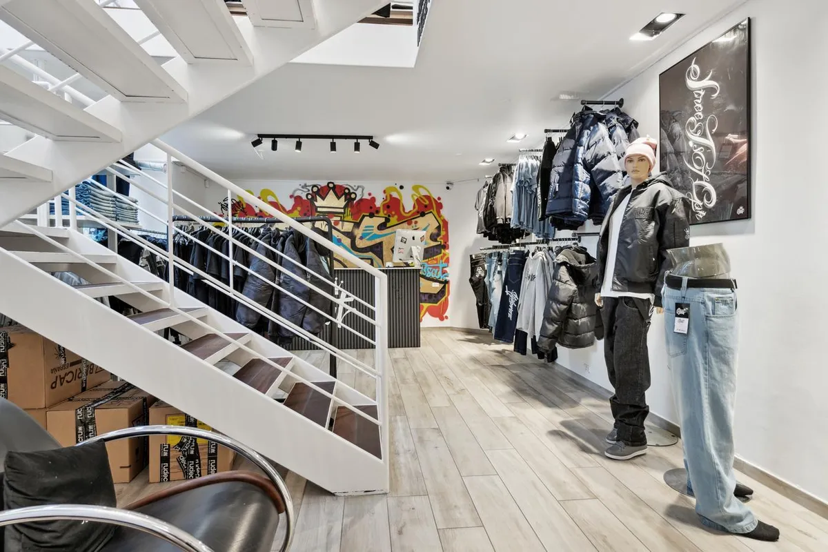 Indbydende tøjbutik med graffiti på væggen og sort og hvidt interiør og et stort sort sæde med pude