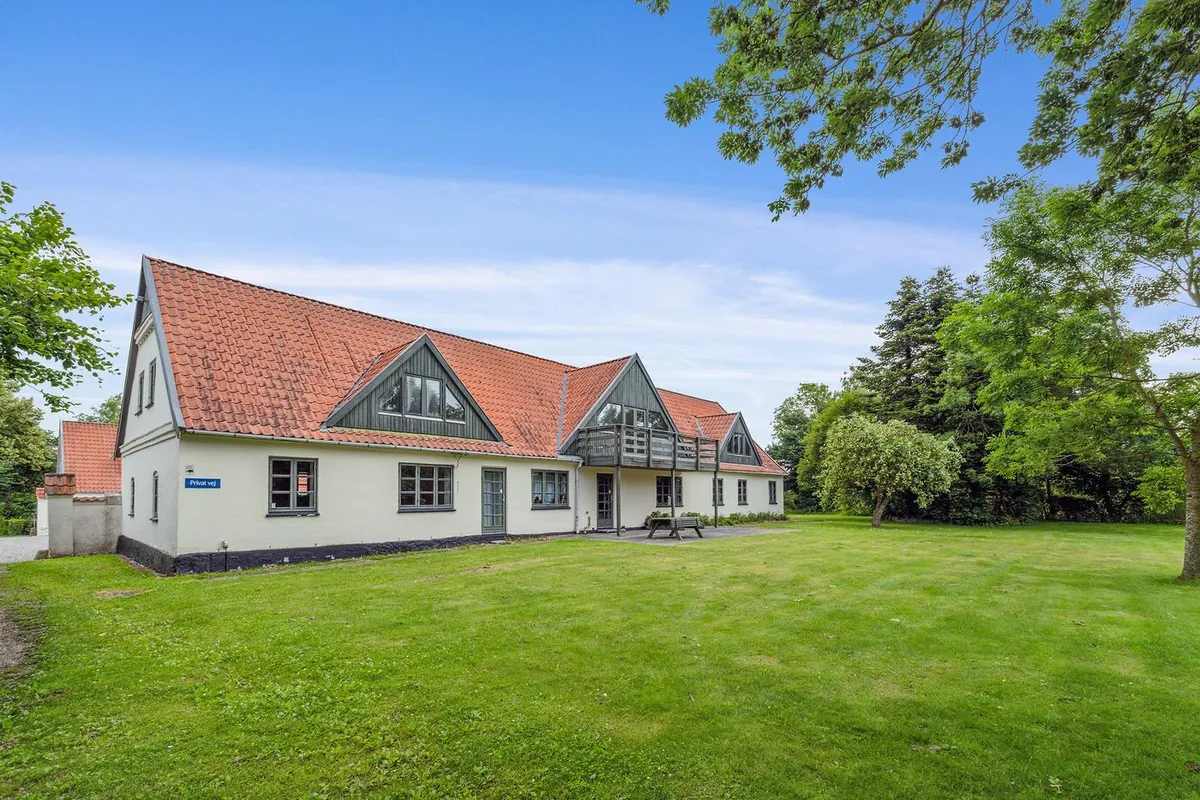 Kontor i grønne omgivelser med to røde tag og lyseruder og en terrasse med udsigt over parken