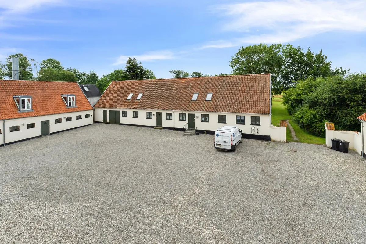 Kontorbyggeri med to sidefløje og parkeringsplads og masser af grønne omgivelser