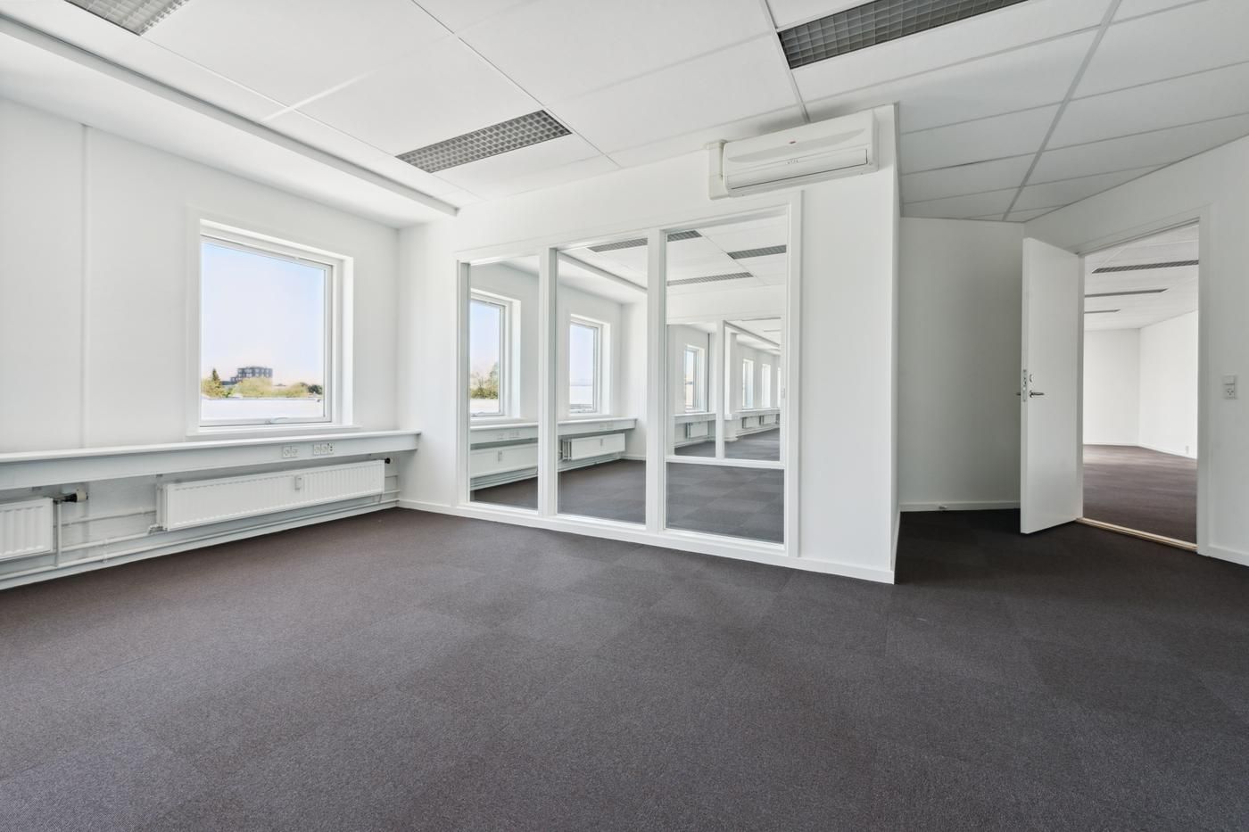 Et hvidt kontor med vinduer og spejle, hvor det er mærkbart tomme og lyst med et højt loft