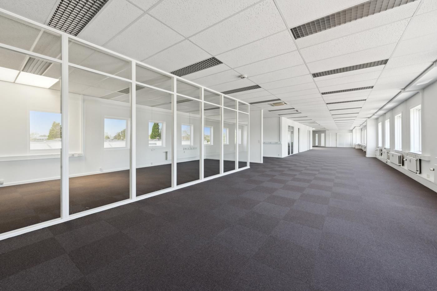 Store, hvide glasruder og gulve med mørke karper er omgivet af en hvid væg med flere små vinduer og en hvid loftsbeklædning
