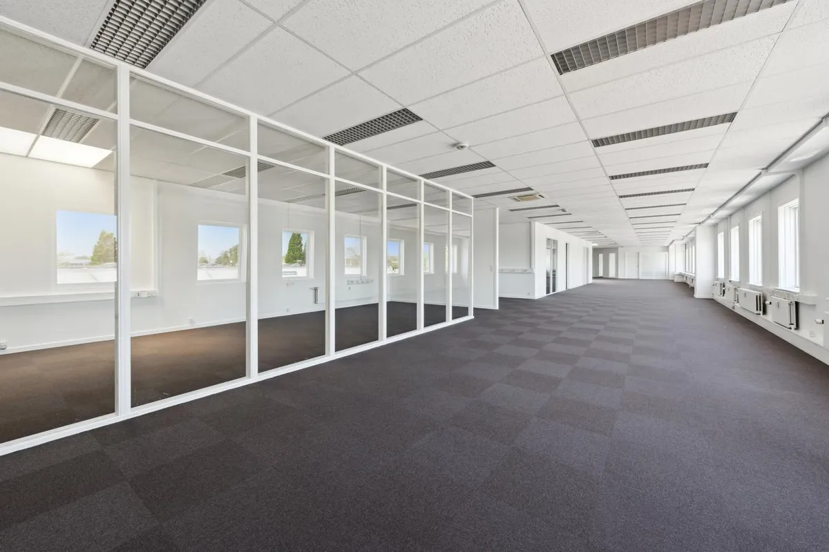 Store, hvide glasruder og gulve med mørke karper er omgivet af en hvid væg med flere små vinduer og en hvid loftsbeklædning