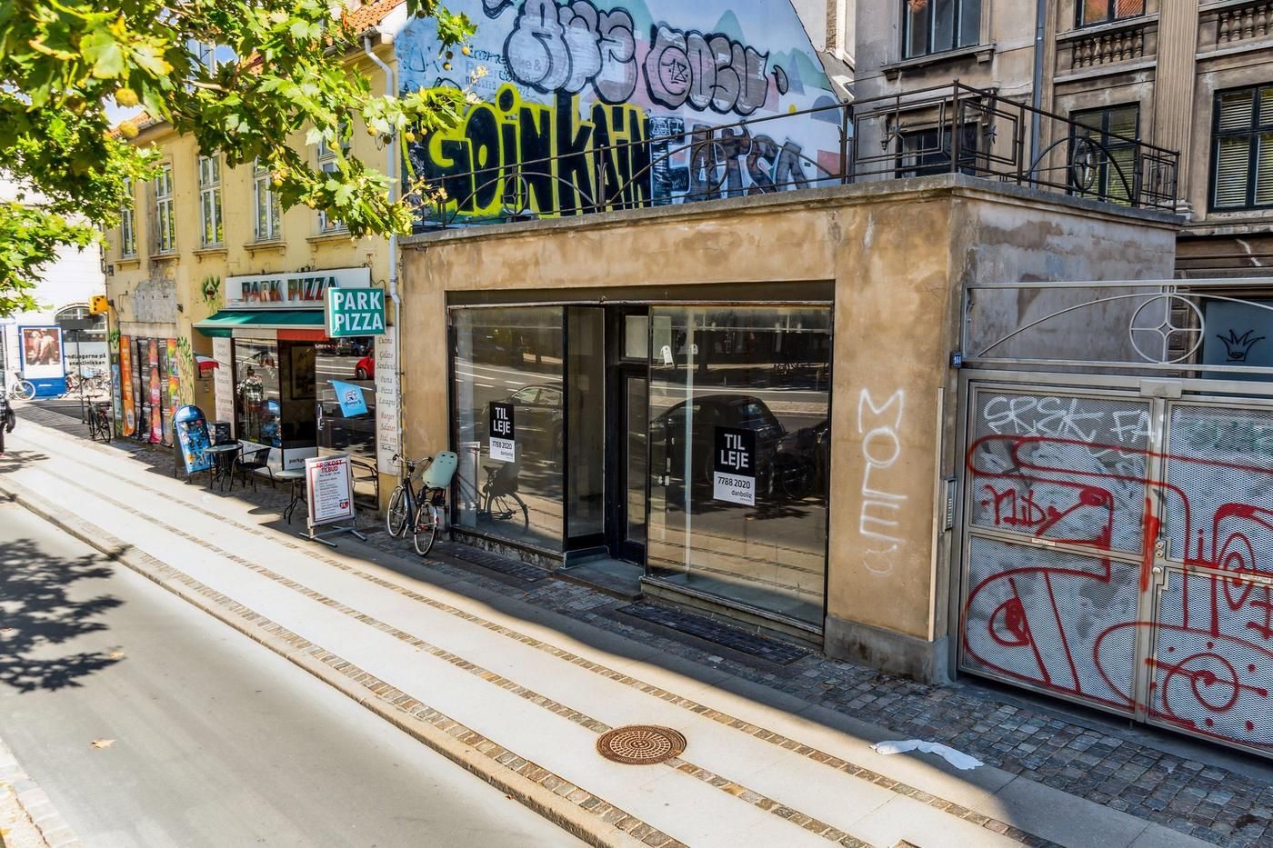 Erhvervslejemål med graffiti på facaden på Østerbrogade, og et vindue med reklameskilt til Park Pizza