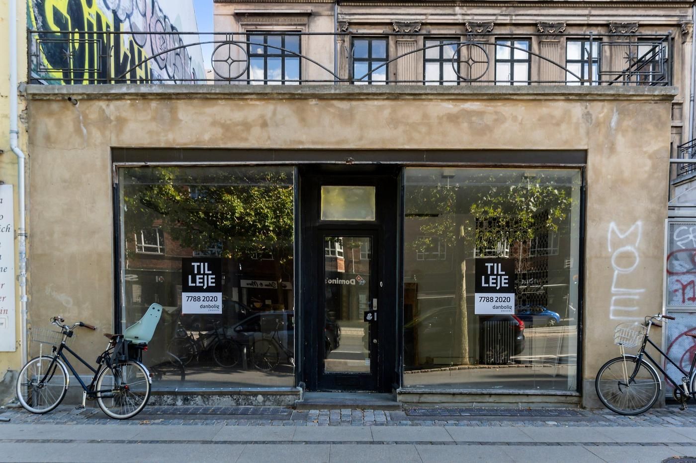 Erhvervslejemål i Østerbro med facadevinduer, to cykler parkeret og tekst "TIL LEJE" i vinduet.