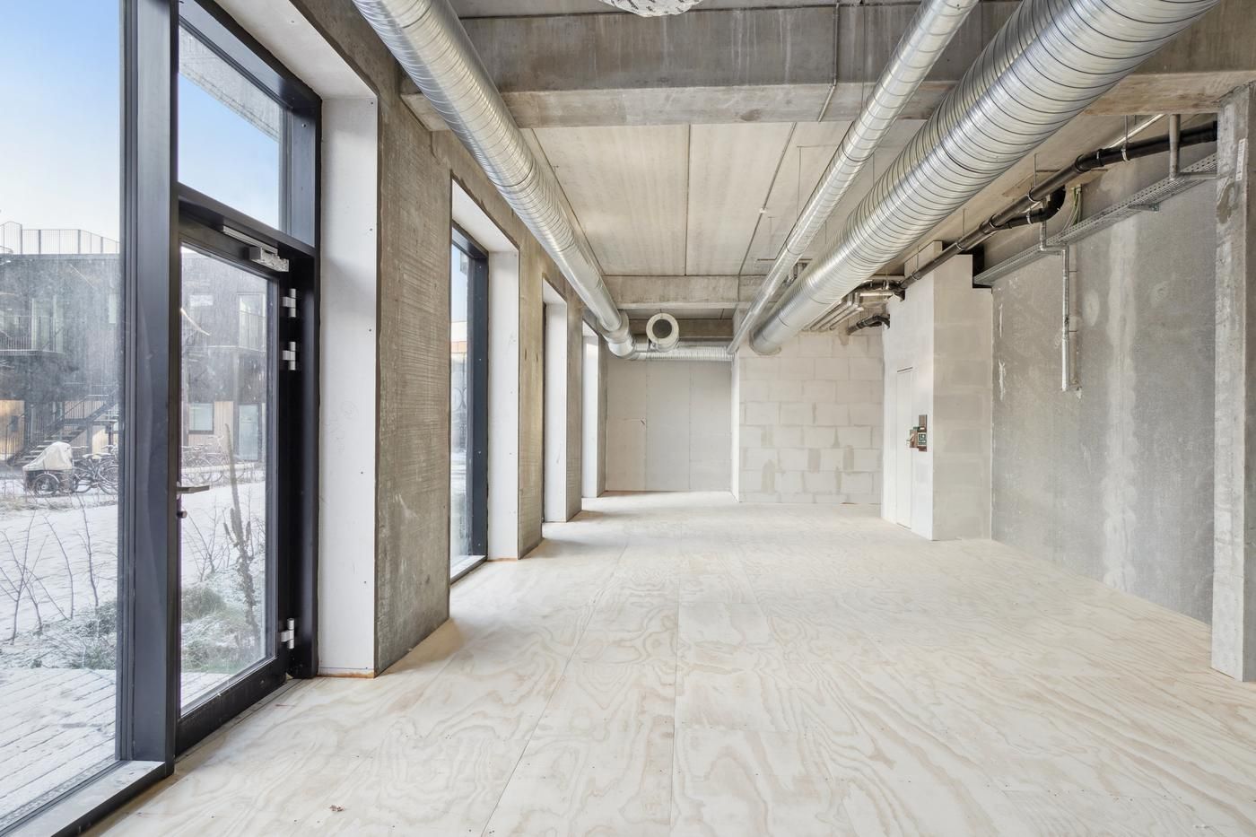 En stor hal med lyse trægulve og stærke betonvægge for at give et industrielt look til kontorlokalet