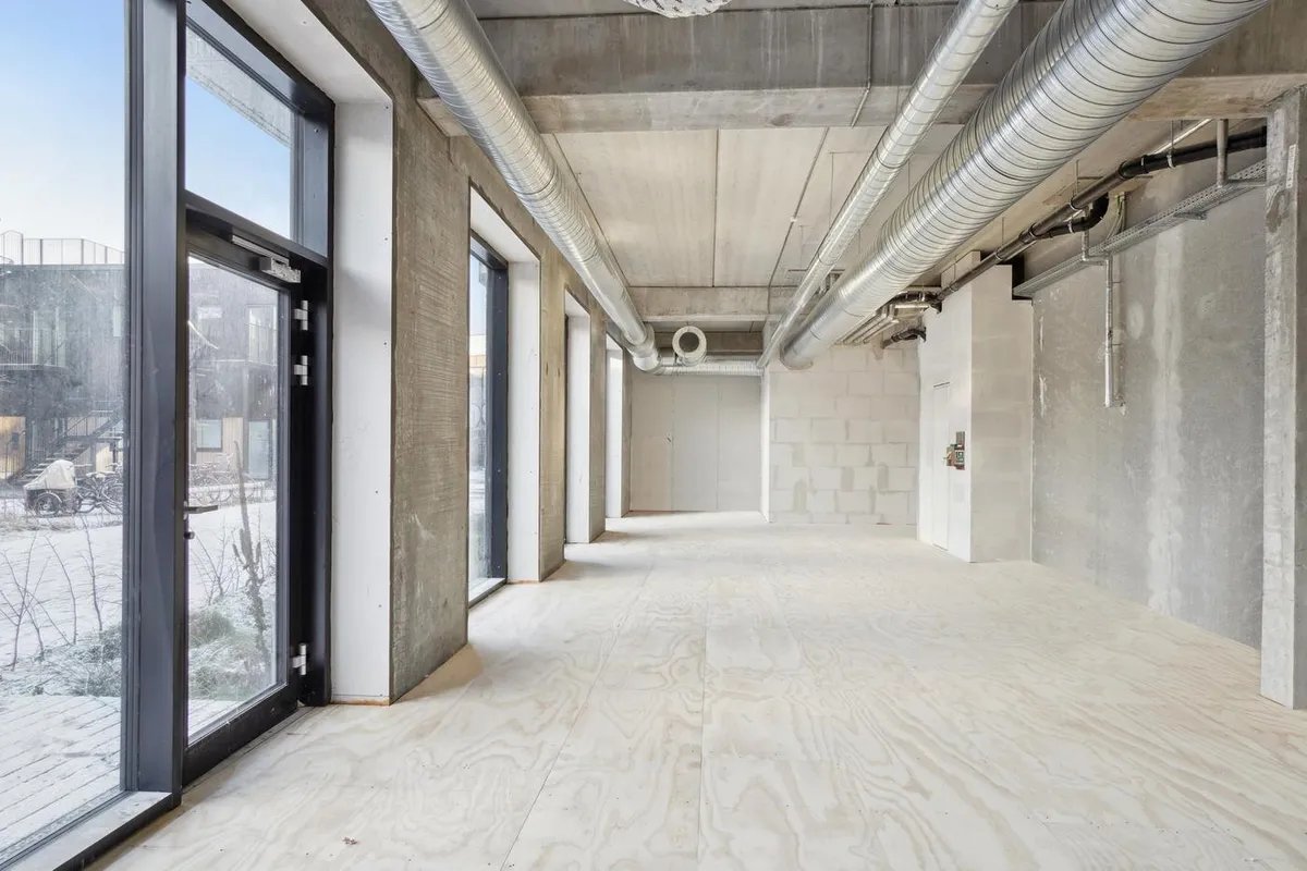 En stor hal med lyse trægulve og stærke betonvægge for at give et industrielt look til kontorlokalet