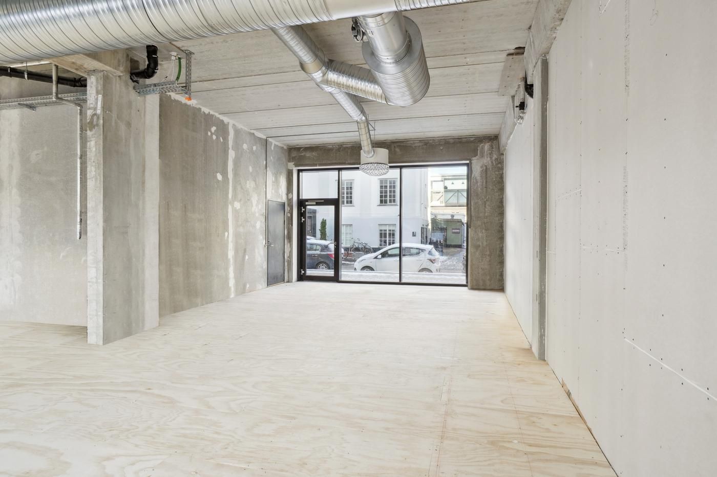 Lejemål på Rentemestervej med glasdøre og åben vej med biler udenfor og en hvid bygning i baggrunden