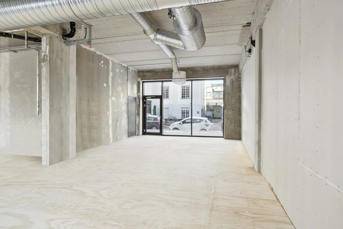 Lejemål på Rentemestervej med glasdøre og åben vej med biler udenfor og en hvid bygning i baggrunden