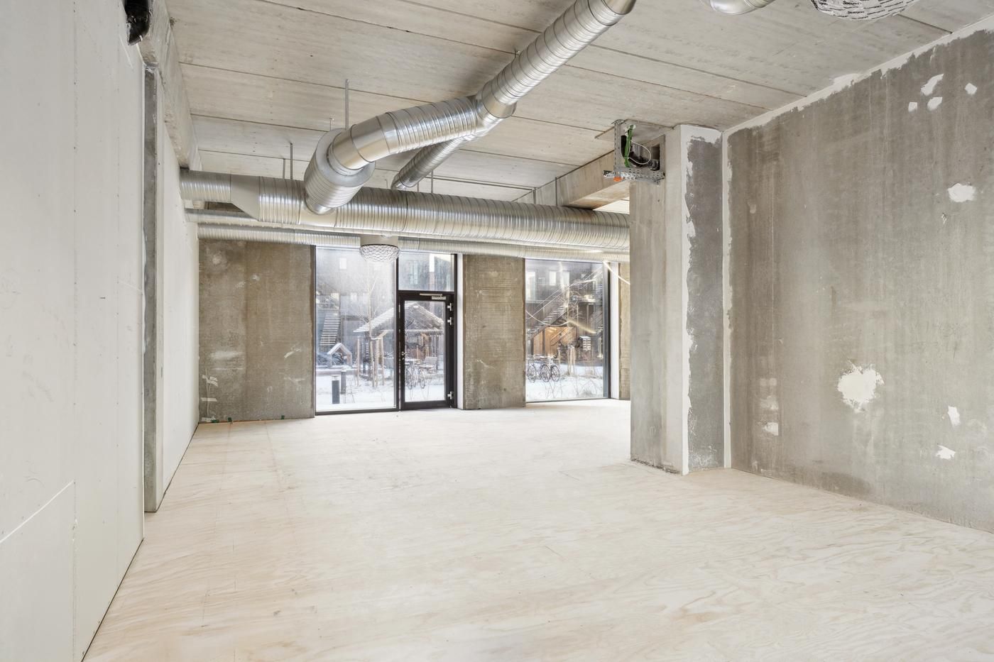 Tomt erhvervslokale med højt til loftet og store vinduer tilstrømmer masser af naturlys ind i rummet