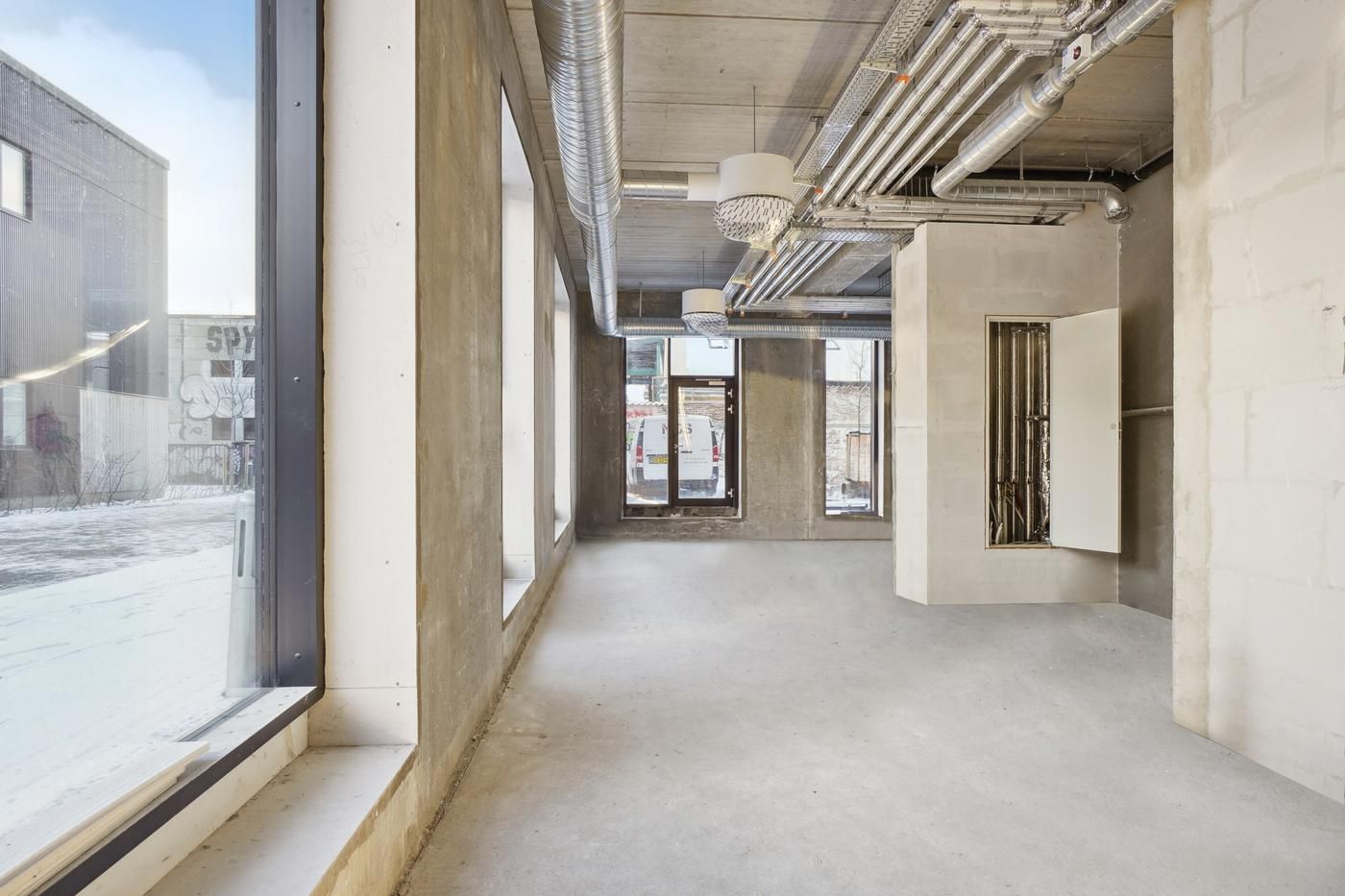 Rømlig industri-inspireret restaurantlokale med høje lofter og lyseruder til eksempelvis pizzarestaurant eller café