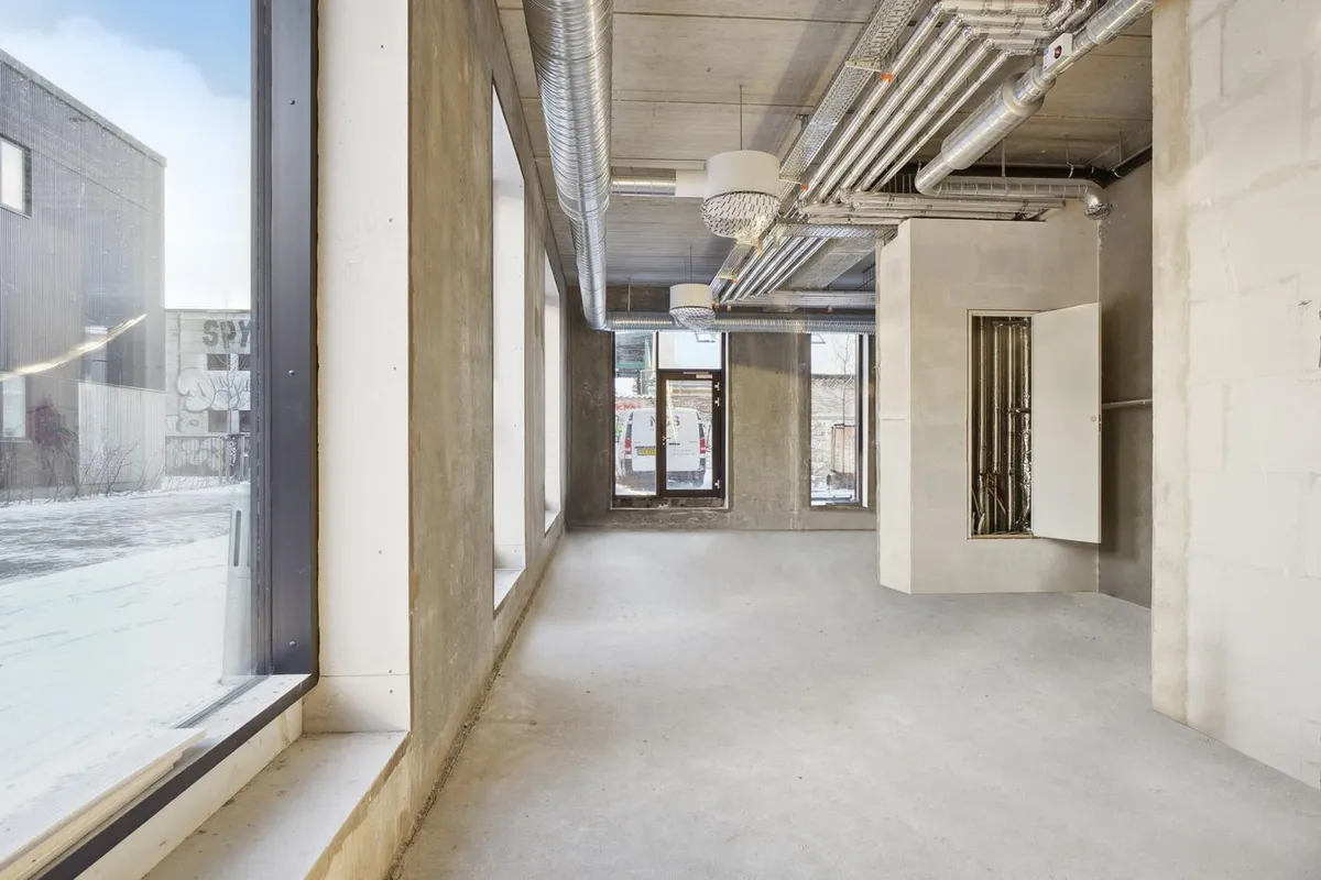 Rømlig industri-inspireret restaurantlokale med høje lofter og lyseruder til eksempelvis pizzarestaurant eller café