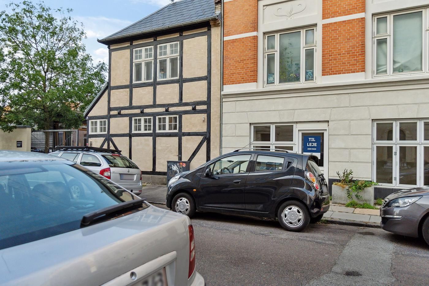 Erhvervslejemål i København med flere biler parkeret foran og smuk facade med røde mursten