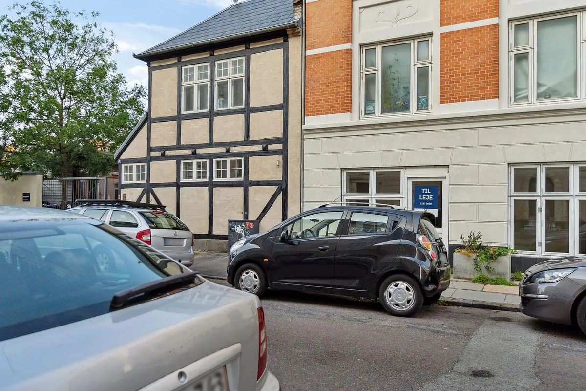 Erhvervslejemål i København med flere biler parkeret foran og smuk facade med røde mursten