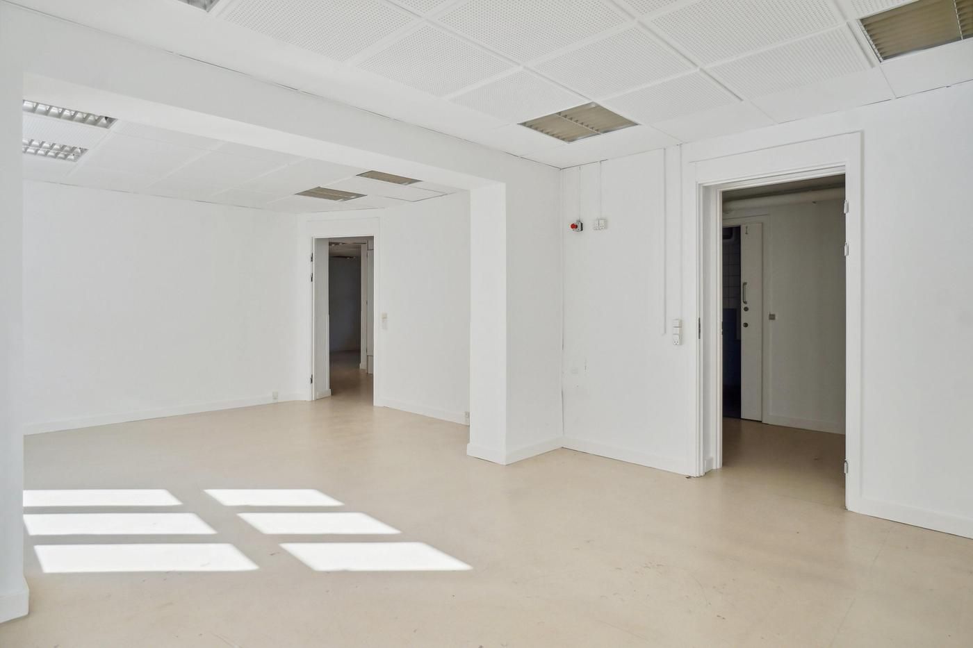 Store og lyse lokaler med hvide vægge og loft samt hvidgule gulvbelægning og vinduer, der kaster lyse stråler på gulvet