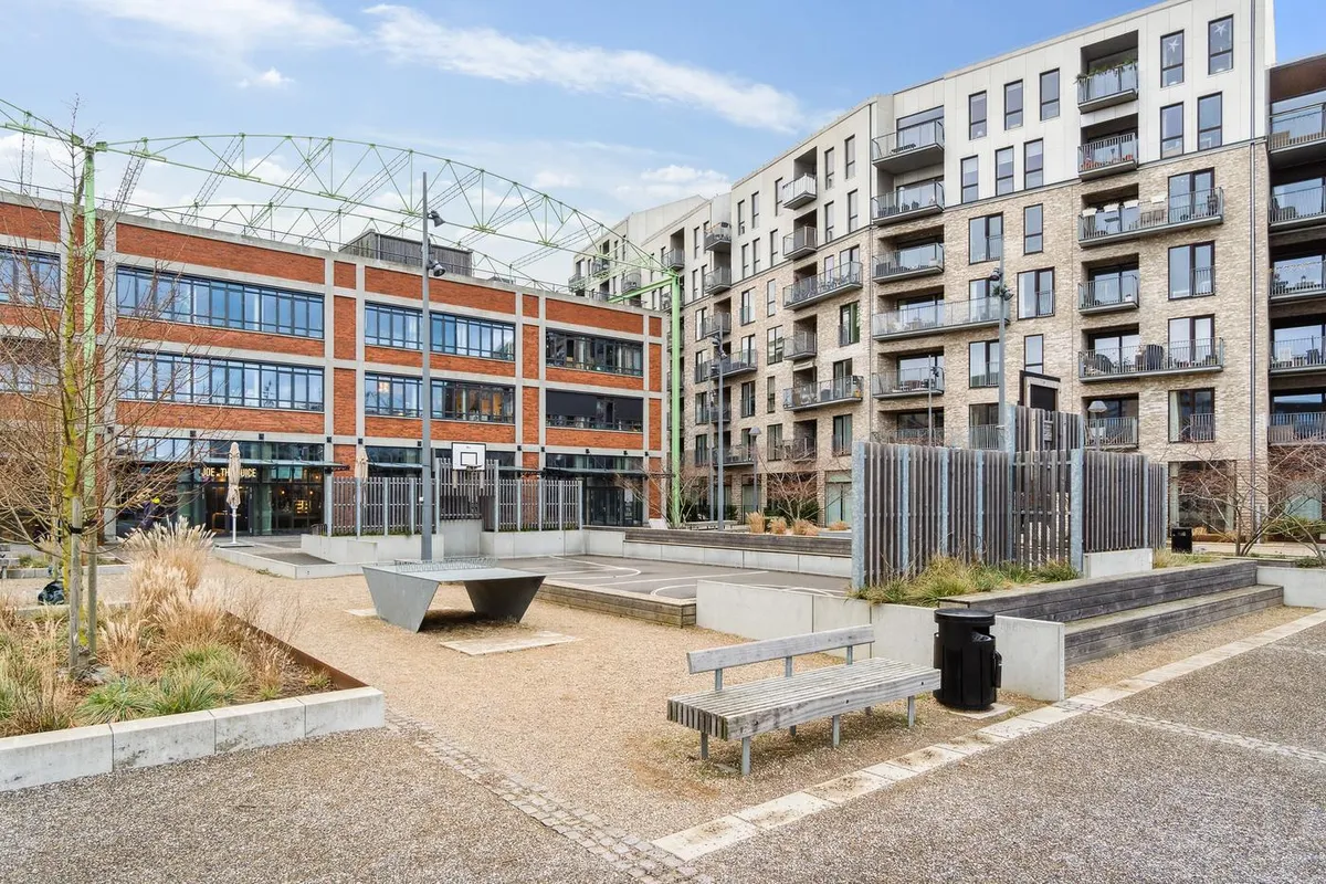 Lejlighedsbygning med terrasser og balkoner og en stor indgang til en café