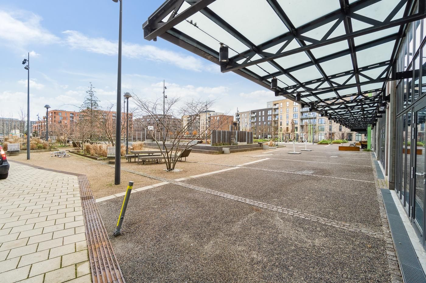 Lejemål med udsigt til bygninger og parkeringsplads samt glasdæk og træer