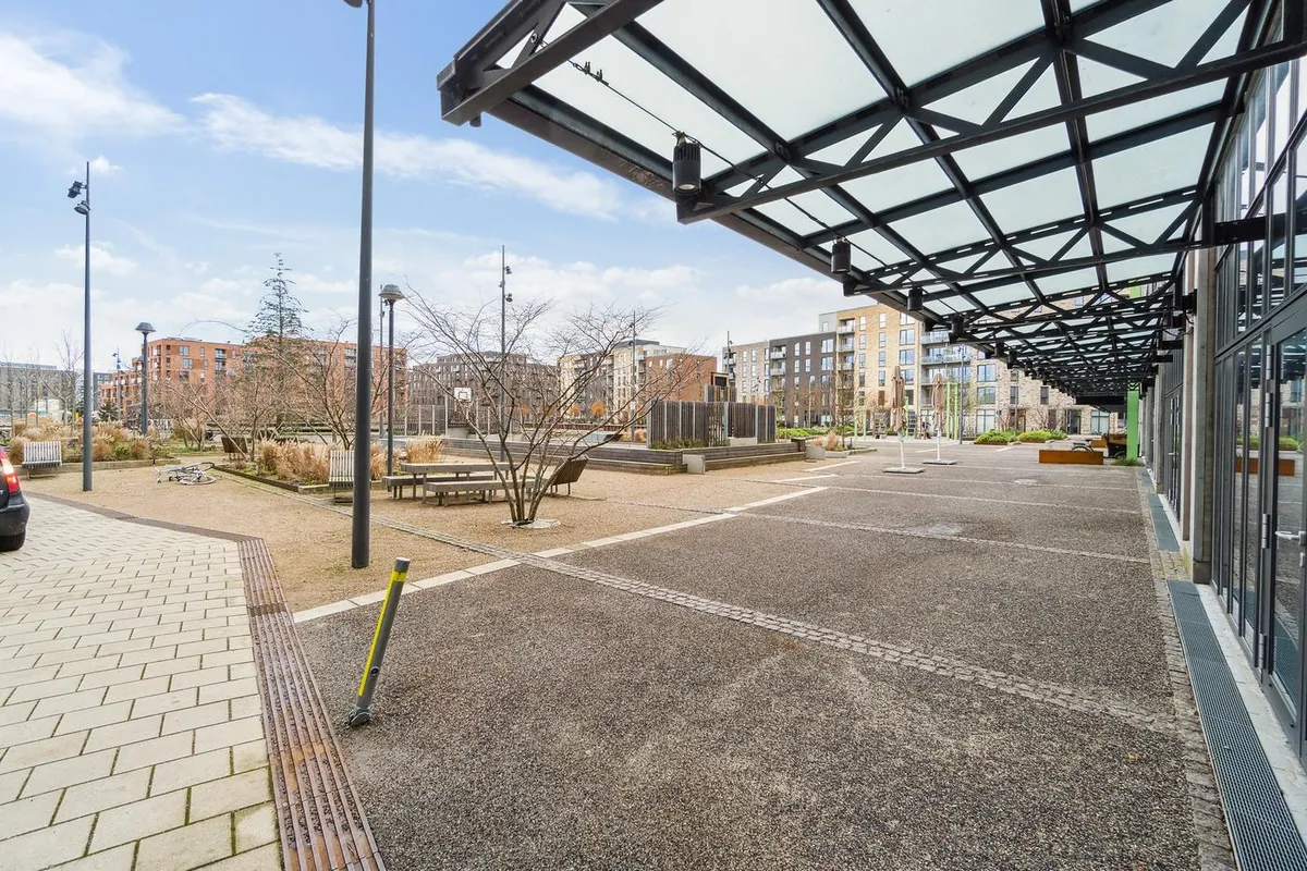 Lejemål med udsigt til bygninger og parkeringsplads samt glasdæk og træer