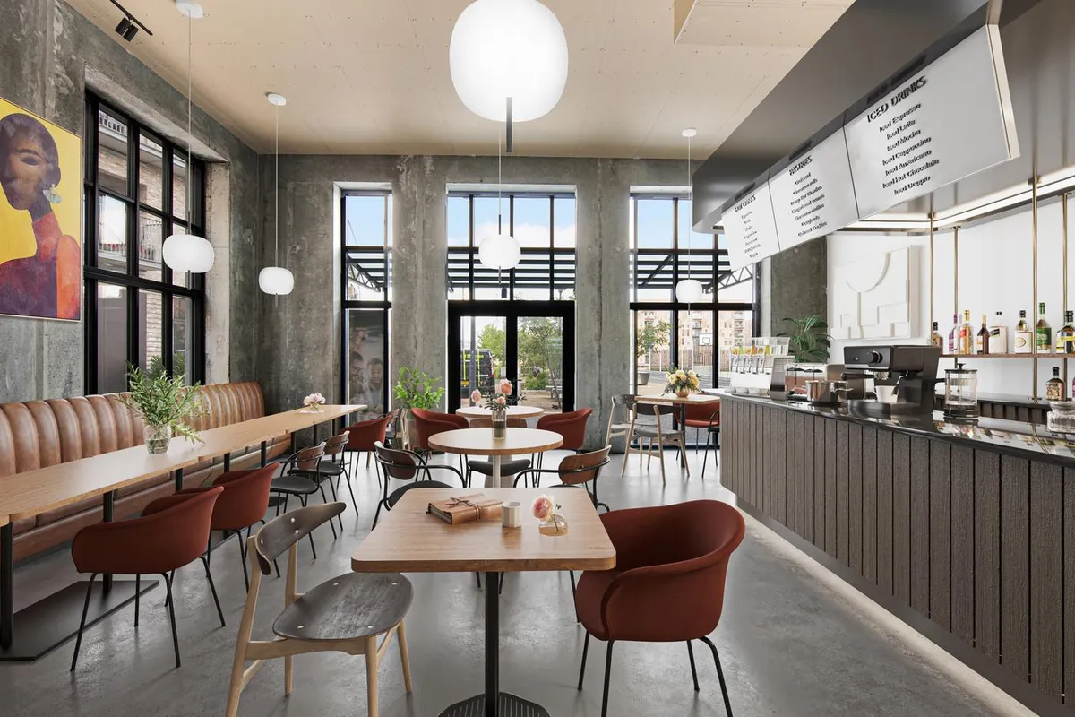 Moderne café med lyse loftslamper og store vinduer, lædersædebanke og runde træborde med røde stole