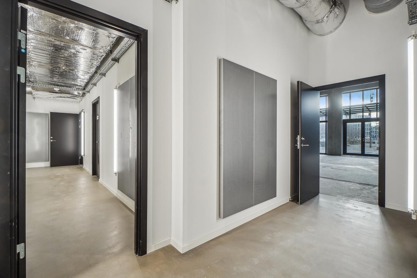 Hallen med åbne døre og lyse vægge, hvor metalelementer og en metalvæg fremhæves for at skabe en industriel stemning