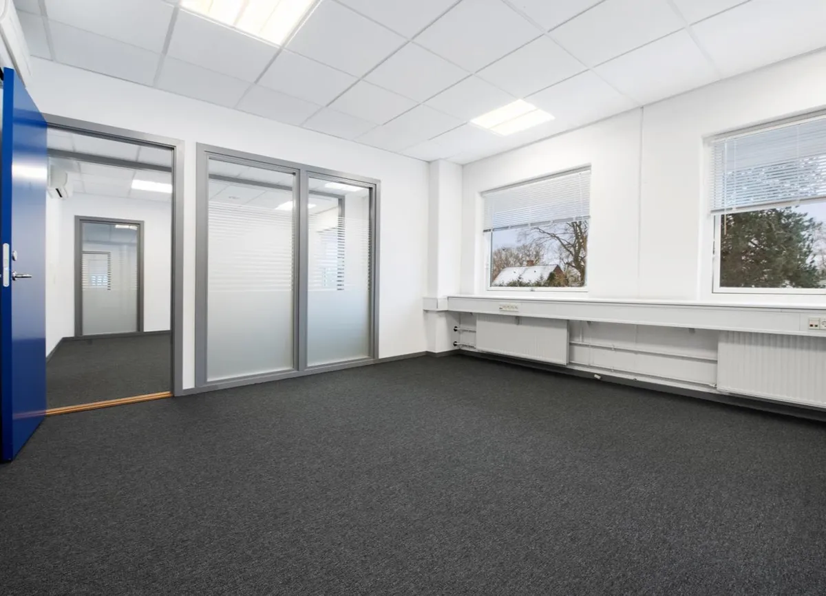 En tom og hvidkontorrum med tre vinduer og en glasdør i lysegråt og blåt med en hvid loftsbeklædning og en hvid gulvbelægning